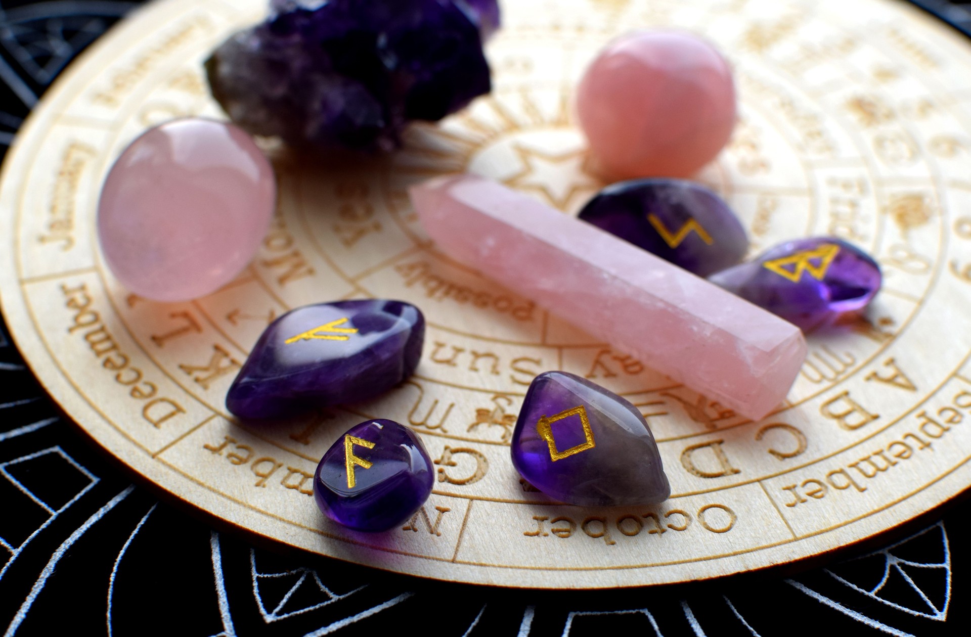 Scandinavian runes made of amethyst and rose quartz crystals on a board with symbols of the zodiac signs. Predictions, witchcraft, spiritual esoteric practice.